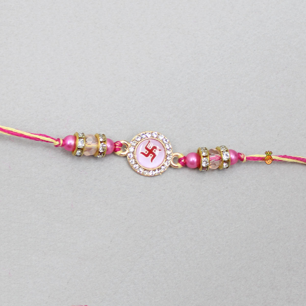 Pink Rakhi Adorned With An Embossed Swastik